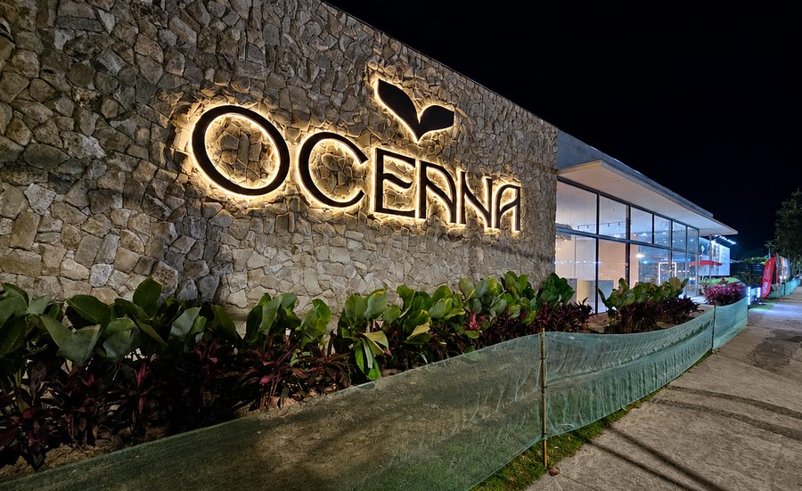 Letra caixa iluminada do empreendimento Oceana, em muro de pedra, à noite
