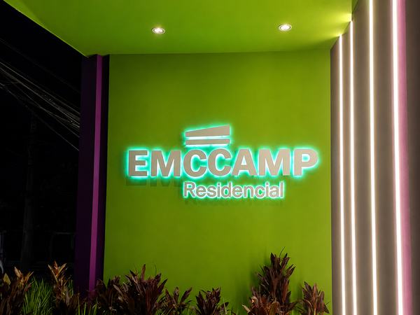 Letreiro luminoso da Emccamp Residencial em parede verde
